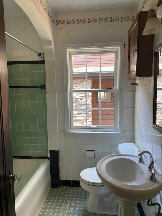 full bath featuring a sink, tile walls, toilet, and bathing tub / shower combination