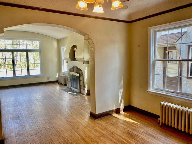 unfurnished living room featuring hardwood / wood-style flooring, baseboards, and radiator