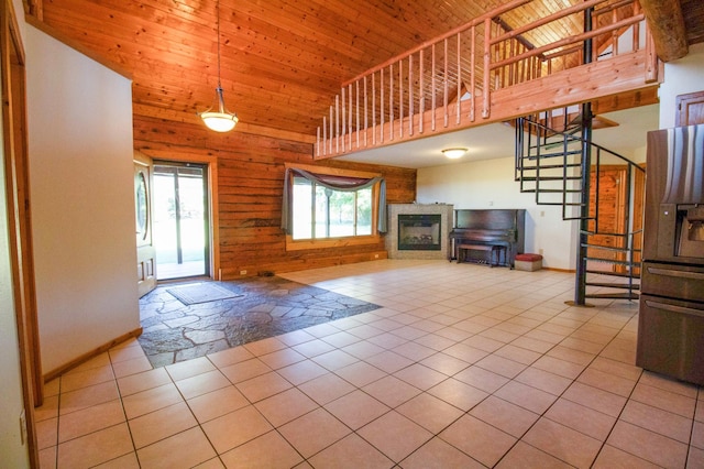 unfurnished living room featuring wood ceiling, light tile patterned floors, high vaulted ceiling, stairway, and baseboards