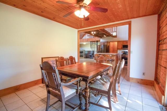 dining area featuring wood walls, wooden ceiling, a ceiling fan, light tile patterned floors, and baseboards