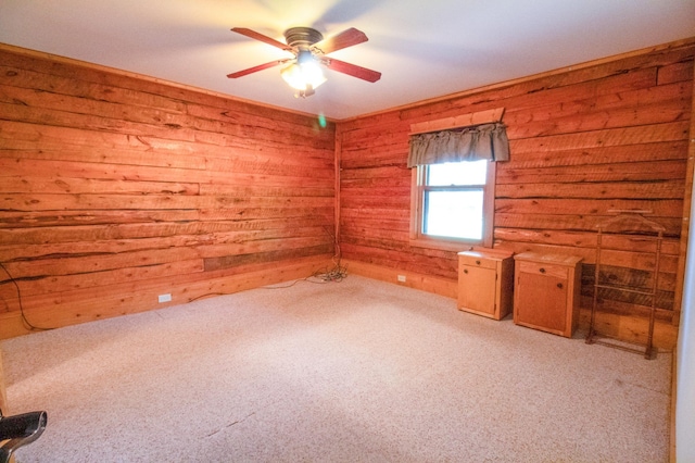 empty room with light colored carpet, wooden walls, and ceiling fan
