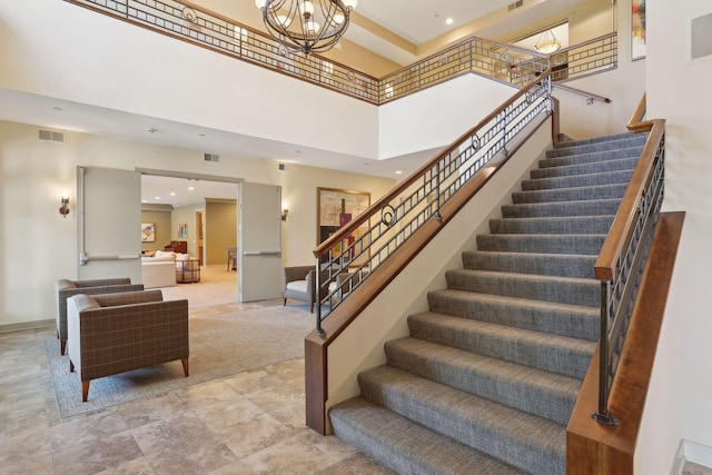 stairs featuring baseboards, a high ceiling, visible vents, and an inviting chandelier
