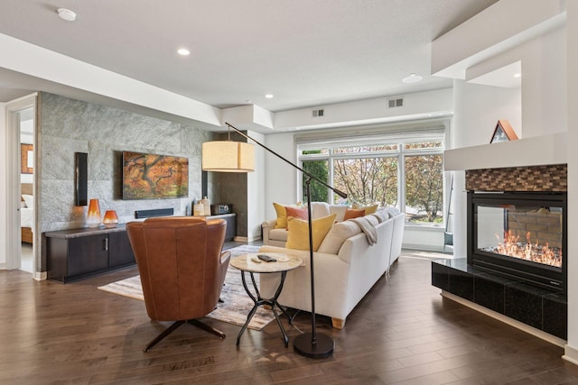 living area featuring a tiled fireplace, recessed lighting, dark wood finished floors, and visible vents
