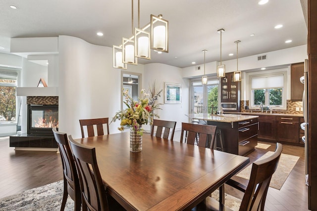 dining area featuring recessed lighting, a fireplace, hardwood / wood-style flooring, and visible vents