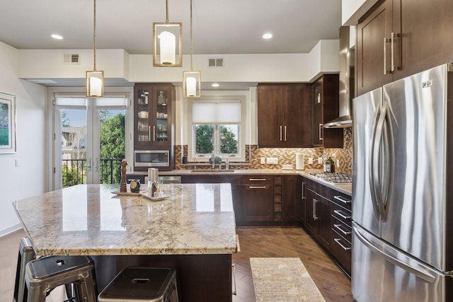 kitchen with visible vents, decorative backsplash, a center island, a sink, and appliances with stainless steel finishes