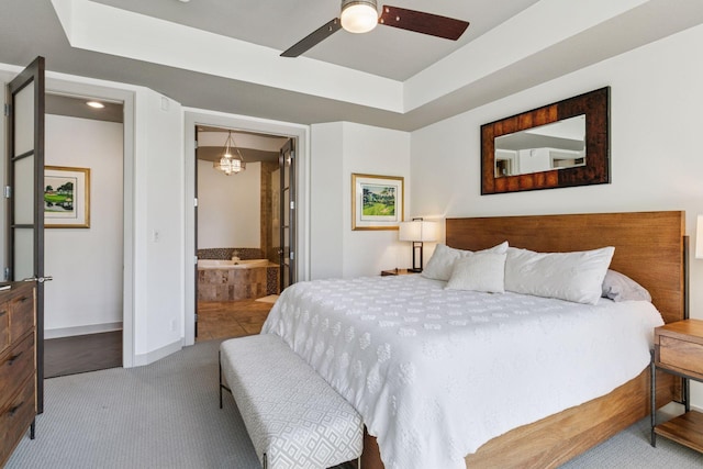 bedroom with a ceiling fan, baseboards, ensuite bathroom, a tray ceiling, and carpet flooring
