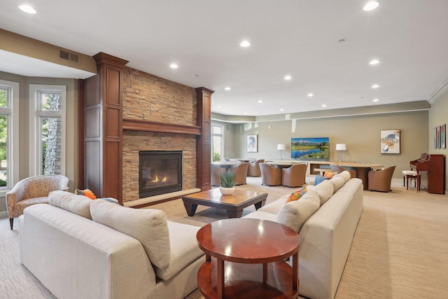 living room featuring recessed lighting, visible vents, a stone fireplace, and light colored carpet
