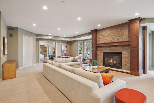 living room featuring a stone fireplace, visible vents, light colored carpet, baseboards, and recessed lighting