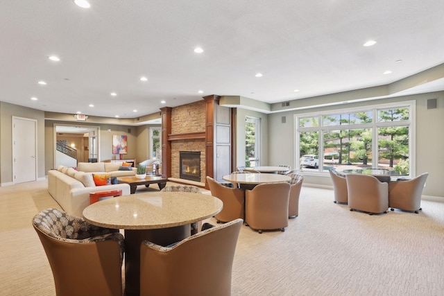 dining space with recessed lighting, a stone fireplace, visible vents, and light carpet
