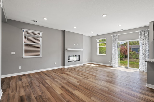 11263 131st Cir N, Dayton, MN 55327 - unfurnished living room featuring a glass covered fireplace, wood finished floors, baseboards, and recessed lighting