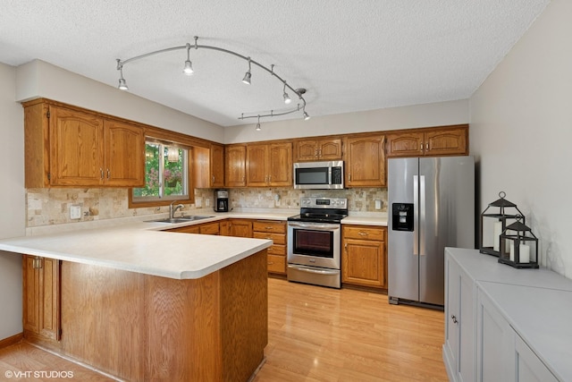 17150 Grenadier Ave, Lakeville, MN 55044 - kitchen featuring stainless steel appliances, brown cabinetry, a peninsula, tasteful backsplash, and a textured ceiling