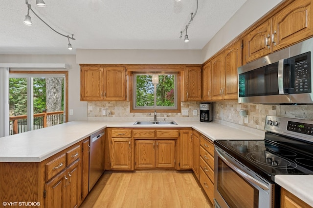 17150 Grenadier Ave, Lakeville, MN 55044 - kitchen with appliances with stainless steel finishes, track lighting, brown cabinetry, light wood-type flooring, and a textured ceiling
