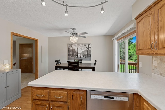 17150 Grenadier Ave, Lakeville, MN 55044 - kitchen with stainless steel dishwasher, a peninsula, light countertops, brown cabinetry, and a textured ceiling