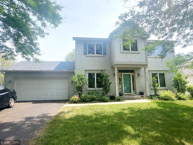 traditional home with asphalt driveway, stucco siding, a garage, and a front yard