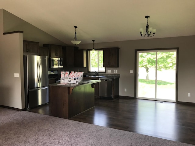 kitchen with baseboards, appliances with stainless steel finishes, dark countertops, and a kitchen breakfast bar