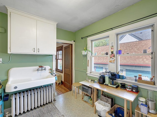 2100 Saint Clair Ave, Saint Paul, MN 55105 - kitchen with radiator, white cabinetry, a sink, and wood finished floors