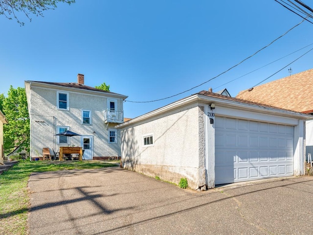 2100 Saint Clair Ave, Saint Paul, MN 55105 - rear view of house featuring a balcony, a detached garage, a chimney, and stucco siding