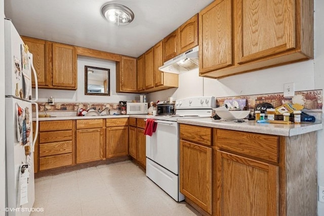 904 Washington St, Saint Croix Falls, WI 54024 - kitchen with brown cabinetry, white appliances, light floors, light countertops, and under cabinet range hood