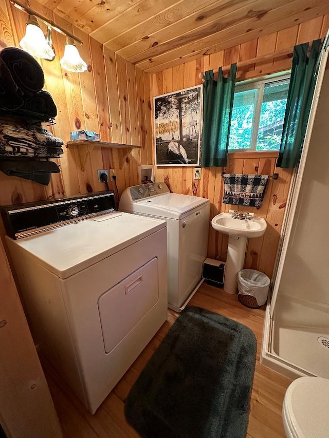 clothes washing area with laundry area, separate washer and dryer, wood walls, wood finished floors, and wood ceiling