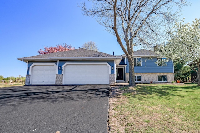 split level home with brick siding, driveway, a front lawn, and an attached garage