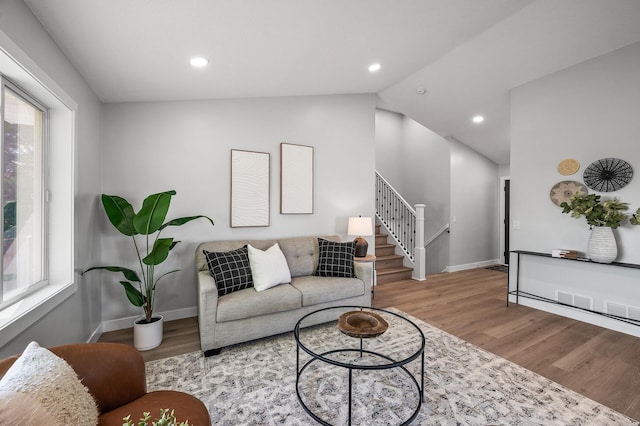 living room featuring stairs, wood finished floors, plenty of natural light, baseboards, and lofted ceiling