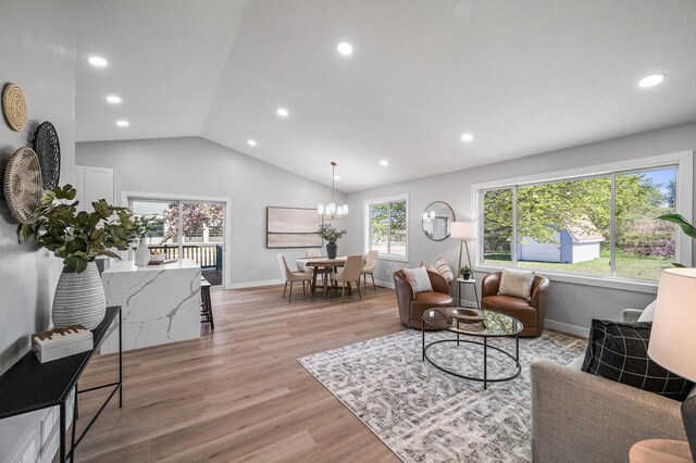 living area featuring recessed lighting, vaulted ceiling, light wood finished floors, baseboards, and a chandelier