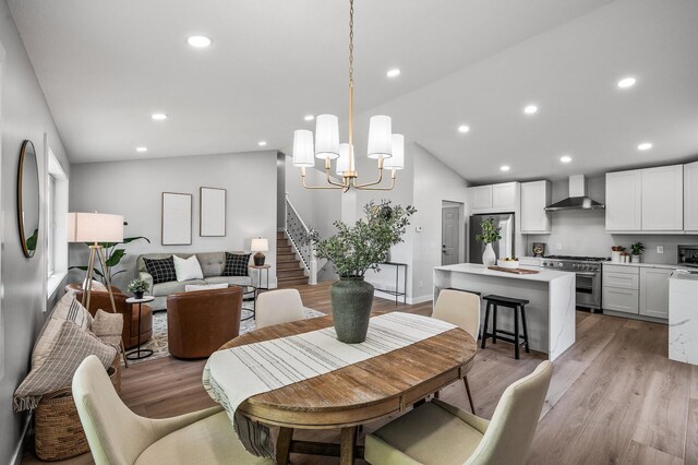 dining area featuring vaulted ceiling, stairway, light wood-type flooring, a chandelier, and recessed lighting