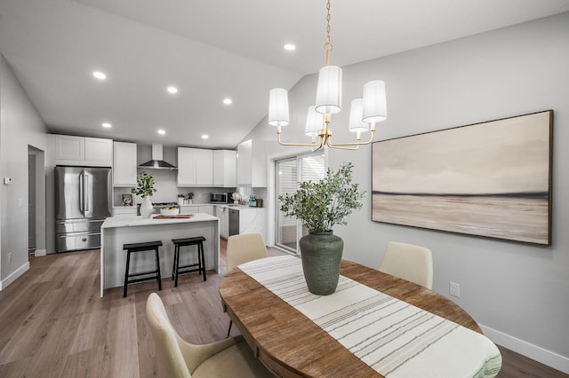dining area with baseboards, a chandelier, vaulted ceiling, wood finished floors, and recessed lighting