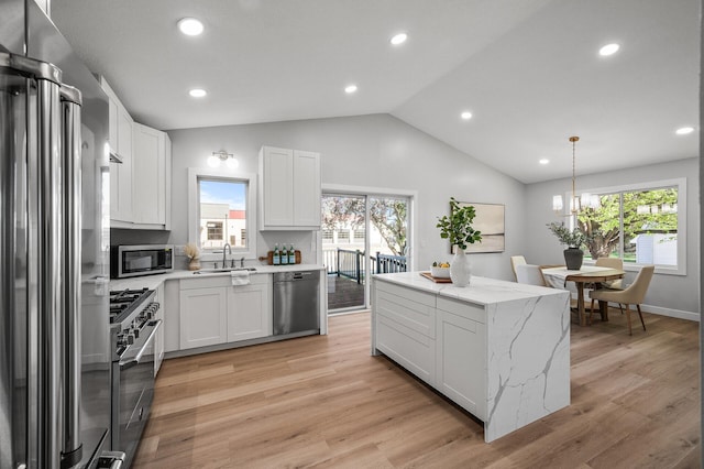 kitchen with stainless steel appliances, a sink, healthy amount of natural light, lofted ceiling, and white cabinetry