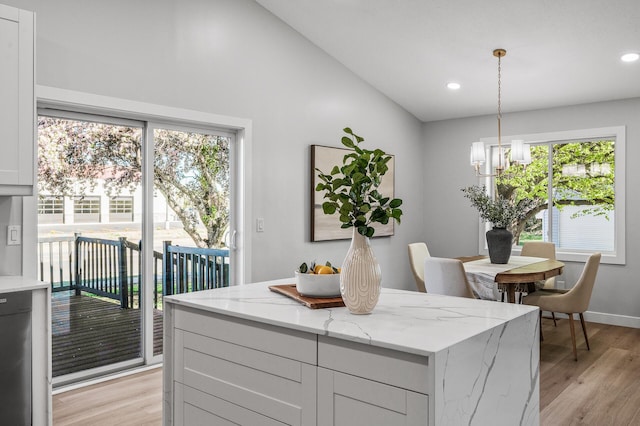 kitchen featuring light wood-style flooring, light stone counters, a chandelier, recessed lighting, and a center island