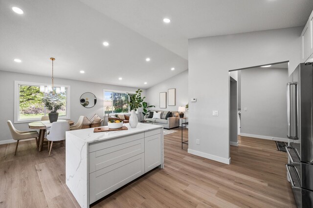kitchen featuring high end refrigerator, white cabinetry, open floor plan, plenty of natural light, and lofted ceiling