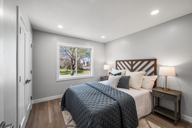 bedroom featuring baseboards, wood finished floors, and recessed lighting