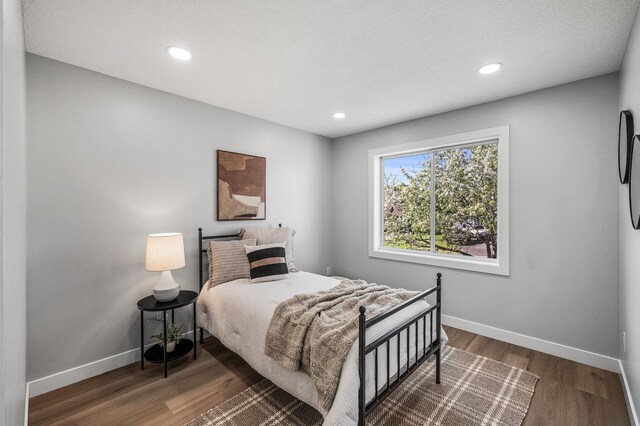 bedroom featuring baseboards, wood finished floors, and recessed lighting