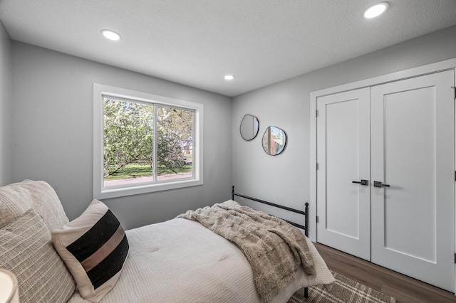 bedroom with dark wood-type flooring, recessed lighting, a closet, and a textured ceiling