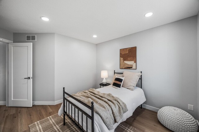 bedroom with wood finished floors, baseboards, and recessed lighting