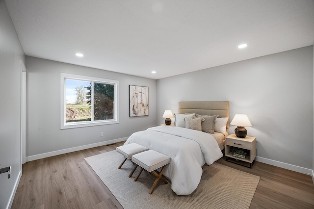bedroom with baseboards, wood finished floors, and recessed lighting