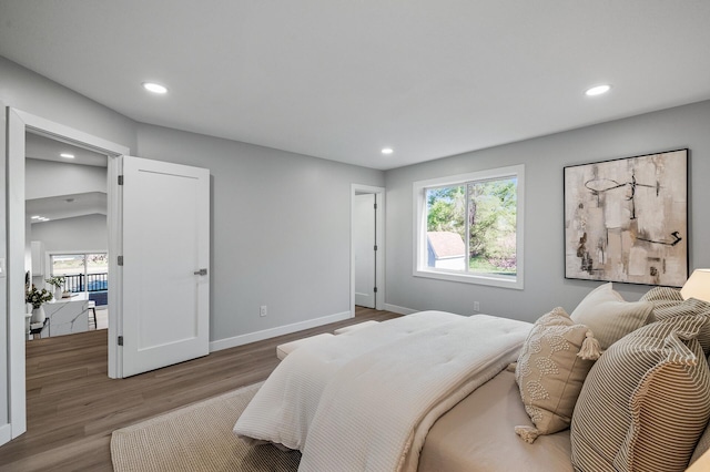 bedroom with recessed lighting, multiple windows, wood finished floors, and baseboards
