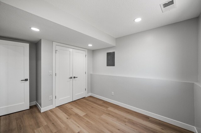unfurnished bedroom featuring wood finished floors, baseboards, recessed lighting, electric panel, and a closet