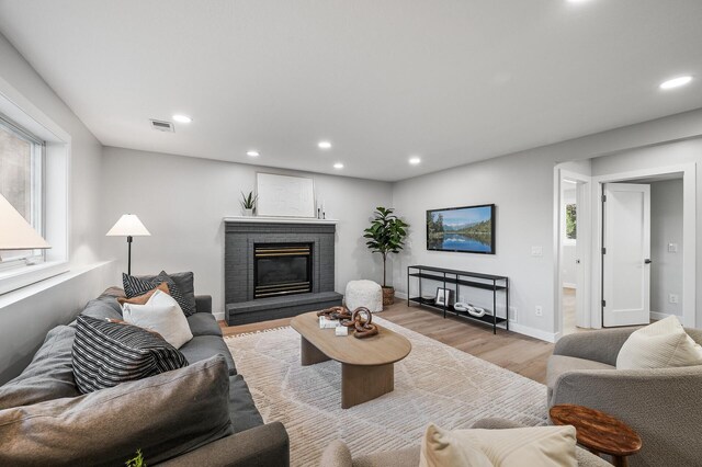 living area featuring recessed lighting, light wood-style floors, plenty of natural light, a brick fireplace, and baseboards