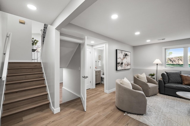 living area featuring recessed lighting, light wood-style flooring, baseboards, and stairs