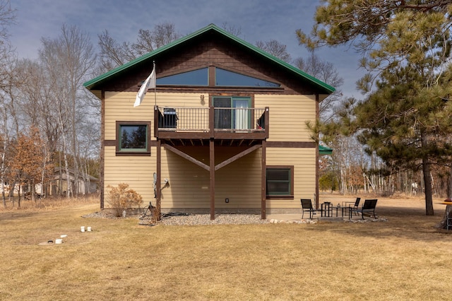 rear view of property featuring a yard and a balcony