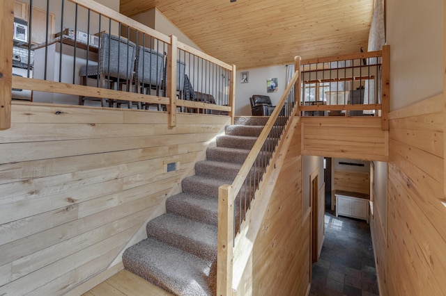 stairs featuring vaulted ceiling, wooden ceiling, and wood walls