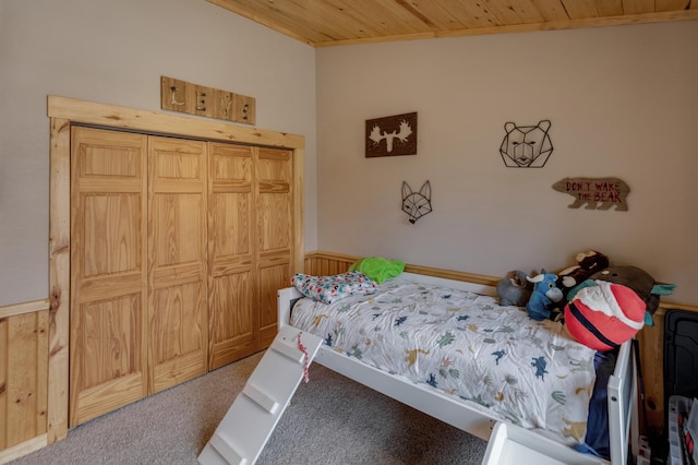 carpeted bedroom with wooden ceiling and wainscoting
