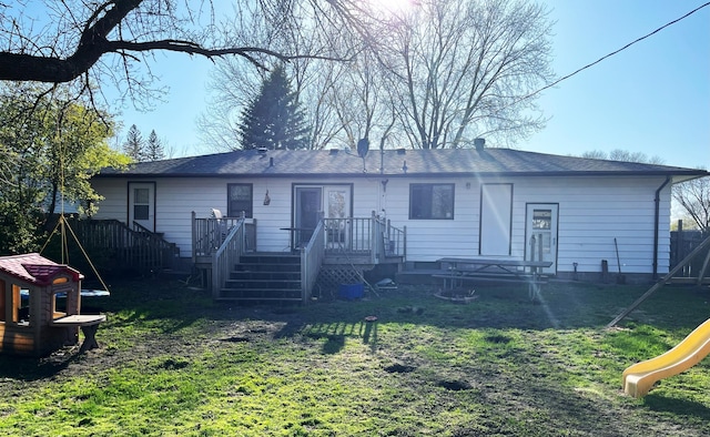 back of house with a playground and a lawn