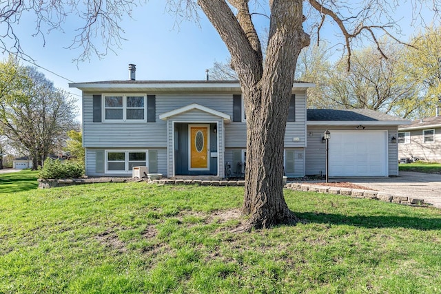 bi-level home with concrete driveway, a garage, and a front yard