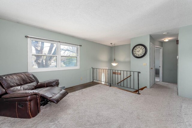 living area featuring an upstairs landing, a textured ceiling, and carpet