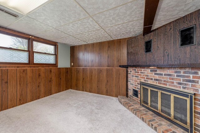 below grade area with wooden walls, carpet floors, and a brick fireplace