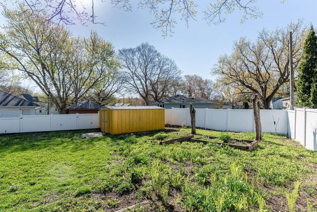 view of yard featuring a storage shed, a vegetable garden, and an outbuilding