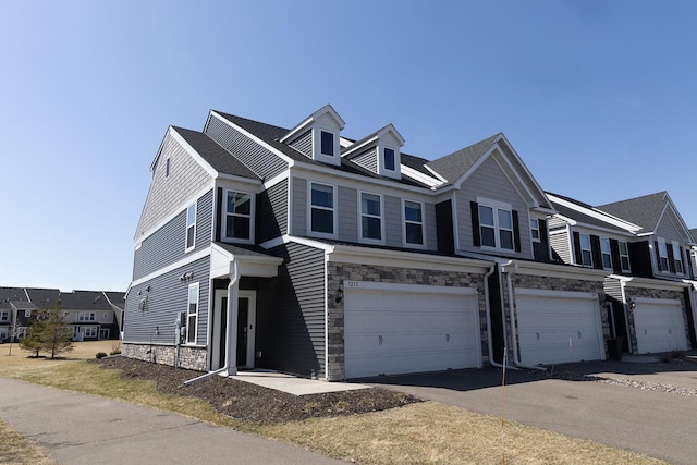 5275 94th Ln N, Brooklyn Park, MN 55443 - townhome / multi-family property featuring aphalt driveway, a garage, stone siding, and a residential view