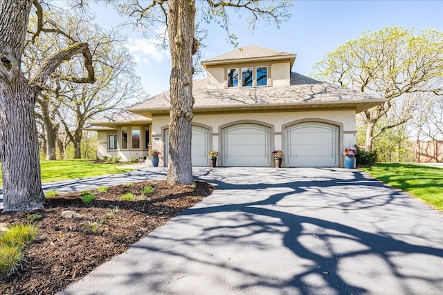 2222 White Oak Ct, Hudson, WI 54016 - view of front of home with stucco siding, driveway, a shingled roof, a front lawn, and an attached garage